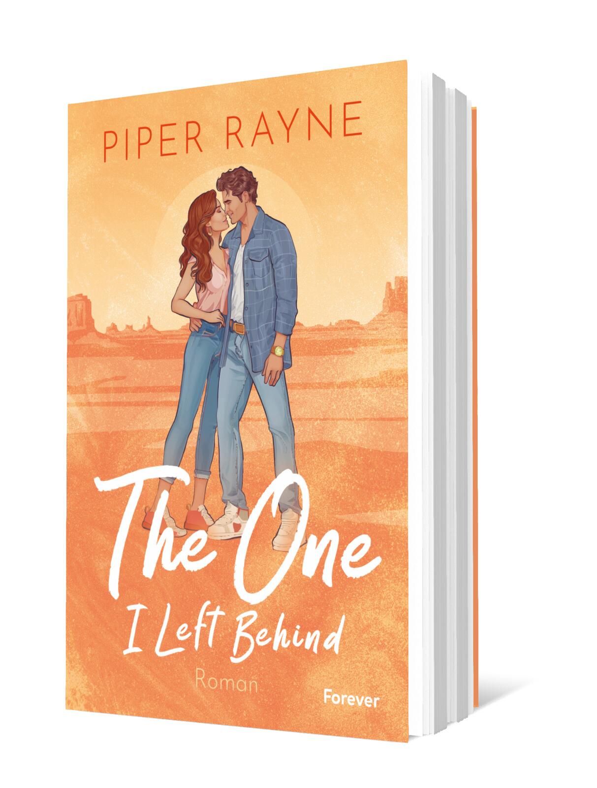 Cover von „The One I Left Behind“ von Piper Rayne: Das Cover zeigt ein Pärchen in der Umarmung vor einer farbigen Wüstenlandschaft, die warmen Orangetöne erzeugen eine romantische Stimmung.